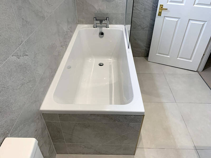 Contemporary St Albans bathroom renovation with grey tiled bathtub and silver fixtures by St Albans Bathroom Fitters