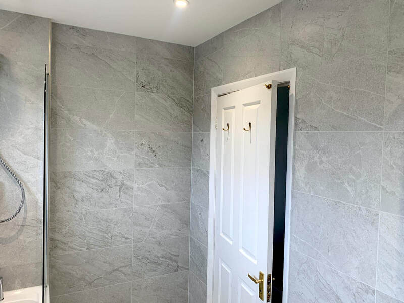 Elegant bathroom shower area renovated by St Albans Bathroom Fitters with grey marble effect tiles and glass door in St Albans