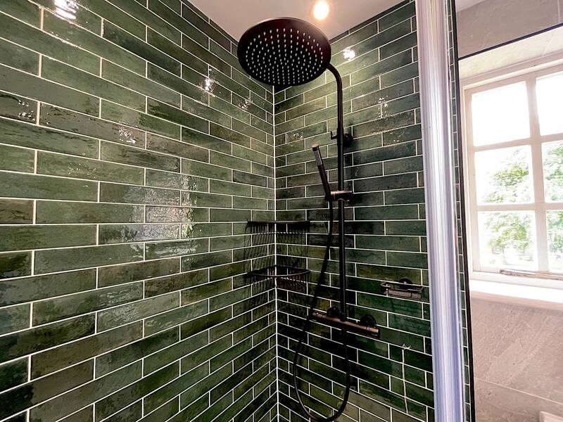 Close-up of green tiles and showerhead in St Albans bathroom.